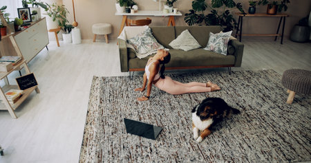 Laptop, girl and yoga with dog in home for stretching, online class and fitness lesson in living room. Yogi, person and cobra pose with virtual exercise video for instructions and holistic wellnessの写真素材