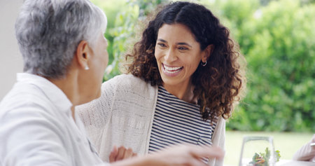 Family, dinner or women with laughing outdoor for funny joke, festive celebration or social gathering. Thanksgiving, happy people or conversation together on patio with love, holiday lunch or bondingの写真素材