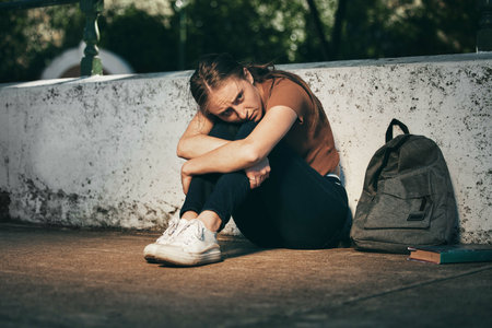 Woman, student and depression in lonely stress, anxiety or mental health problems in the outdoors. Sad and depressed female teenager in distress, loneliness or trouble at school or universityの写真素材