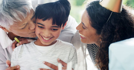 Birthday party, family and hug child for celebration by home with surprise gathering and bonding together. Happy people, boy kid and embrace for special event wish with kiss, relationship and supportの写真素材