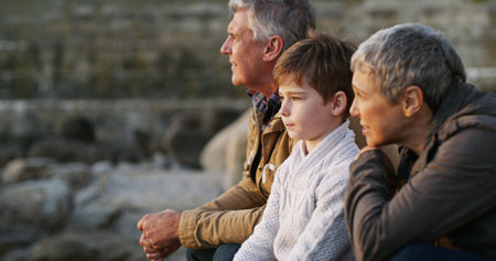 Grandparents, grandchild and relax with view of beach for family holiday, happy memory and travel adventure. Senior people, boy child and sea scenery for connection, bonding and sightseeing natureの写真素材