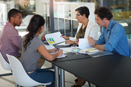 Business people, analytics and statistics with chart for meeting, company results or strategy at office desk. Group, employees or analyst with team, graph or documents for data review or outcomeの写真素材