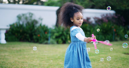 Black child, girl and bubbles in garden for fun, game and childhood development at home. Young kid,...