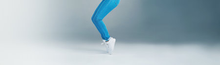 Legs, person and jump with fun in studio with energy, dancing movement and hip hop performance. Dancer, art and balance with creative routine, competition winner and entertainment on gray backgroundの写真素材