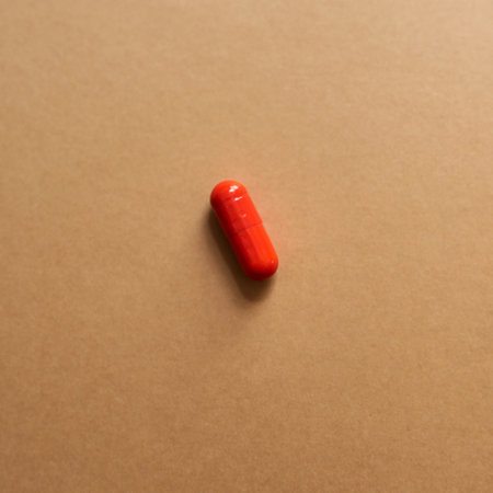 Red, medicine and drugs for health in studio with healthcare wellness, medical painkillers and prescription. Pills, tablets and addiction with treatment, pain remedy and recovery on brown backgroundの写真素材