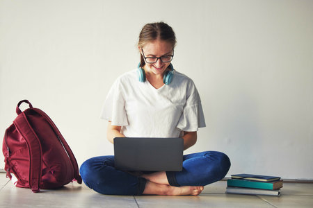 Education, laptop and woman with books on a floor for research, examination and preparation, happy...