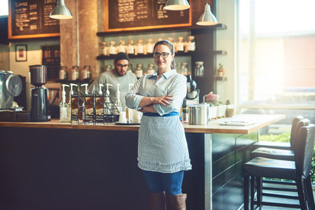 Crossed arms, woman and portrait of waitress in restaurant with confidence for food industry. Happy, pride and server from London with smile for hospitality career in cafe with professional service.の写真素材