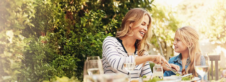 Help, mother and child at outdoor lunch with smile, thanksgiving and family eating together in backyard. Care, mom and daughter at table for garden picnic with food, happy bonding and love on bannerの写真素材