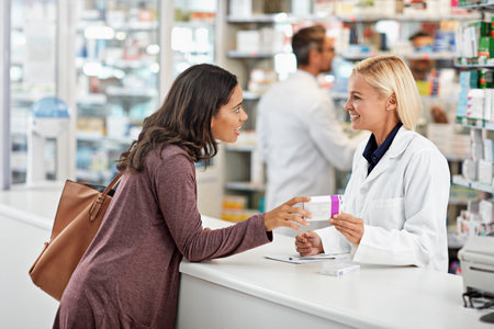 Drugstore, woman and consulting pharmacist by counter for pills side effects, prescription drugs dosage and advice. Friendly, expert and customer service in pharmacy with medication box informationの写真素材
