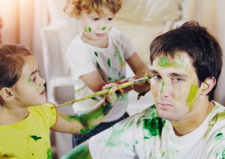 Father, kids and face painting in home for creativity, game and siblings with ADHD. Man portrait, children and facial art in living room for family bonding, relationship growth and skills developmentの写真素材