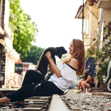 Woman, person or pet on railway track for travel with playing, exploring together or companion on holiday. Tourist, happy or fun with dog on vacation for sightseeing, loyalty or adventure in Vietnamの写真素材
