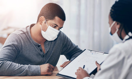 Face mask, patient and doctor with clipboard in hospital for health insurance, medical checklist or consultation. Healthcare, man or professional with feedback on diagnosis or treatment plan checkupの写真素材