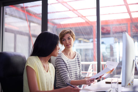 Business, women and teamwork with documents at office for report, feedback and reviews as data scientist. People, employees and meeting with computer or statistics for market research and revenueの写真素材