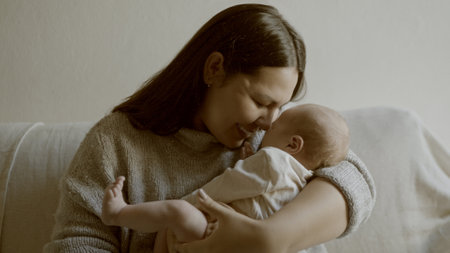 Bond, love and mom with her newborn on a sofa for relaxing in living room of family home. Smile, care and young mother holding her infant, baby or child with happiness in lounge for resting in house.の写真素材