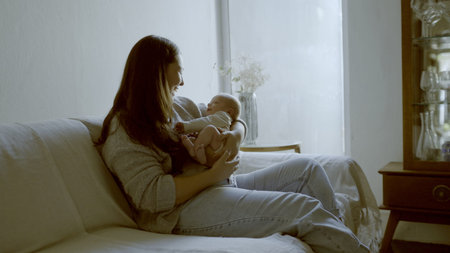 Smile, love and mom with her newborn on a sofa for relaxing, bonding and resting in living room....