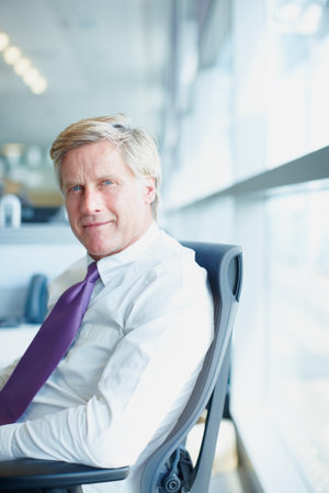 Portrait, business and mature man in office, confidence and career ambition with financial growth. Face, economy analyst and accountant in workplace, pride and corporate professional on chairの写真素材
