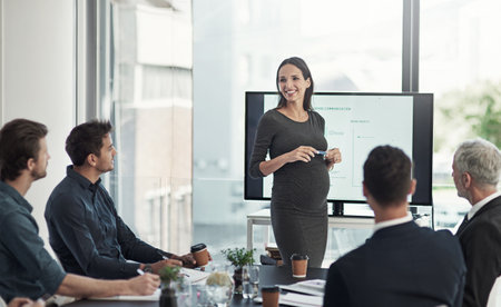 Presentation, meeting and pregnant business woman with team for feedback, finance statistics and review. Corporate, speaker and workers with graph for planning, company insights or growth in workshopの写真素材