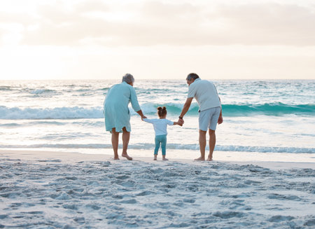 Grandparents, back or holding hands at beach with baby, love or trust in family, retirement or nature together. Bonding, travel or child with senior people or ocean on outdoor holiday vacation tripの写真素材