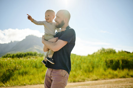 Baby, pointing and father walking in a field, happy and bonding in nature with love. Hug, carrying and parent with child in the countryside for fun, travel and vacation, walk and learning in Mexicoの写真素材