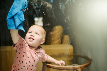 Kid, washing and cleaning window in home for hygiene, health or wellness. Chores, child and toddler,...