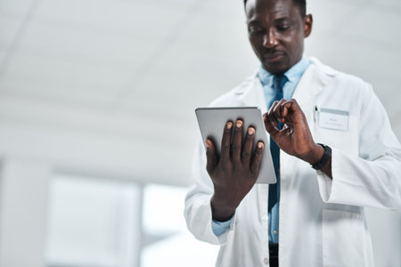 Healthcare, thinking and African doctor with tablet for online patient report, results review and diagnosis. Black man, medical research and communication in hospital, clinic or health facilityの写真素材