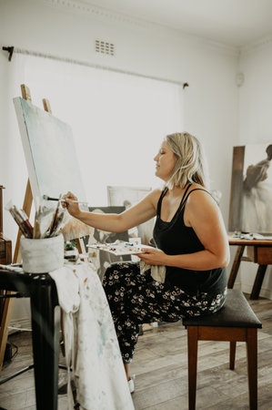 Art, creativity and painting, happy woman in studio at home with brush, canvas and inspiration with color. Paint, tools and talent, professional artist with vision and freedom for creative work ideasの写真素材