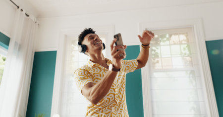 Man, winner and dance with phone for good news, college acceptance and celebration in home. Achievement, victory and opportunity with student in living room for university scholarship and energyの写真素材