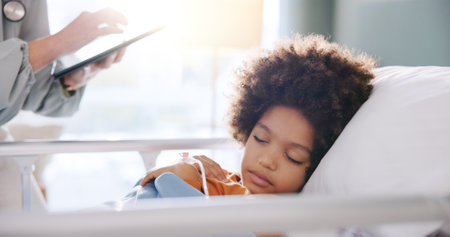 Hospital, doctor on tablet and child sleeping in bed for consulting, checkup and vitals for rehabilitation. Healthcare, pediatric and boy resting for medical service, diagnosis and surgery recoveryの写真素材
