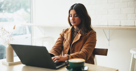 Woman, laptop and typing with remote work at coffee shop with proposal, freelance and copywriting job. Person, computer and editor with feedback, project management and start morning at restaurantの写真素材