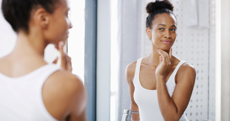 Confidence, woman and skincare in home mirror with anti aging treatment results, glowing skin and natural beauty. Reflection, person and satisfaction with face hydration, wellness and morning routineの写真素材