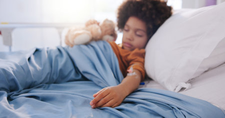 Kid sleeping, hospital bed and sick teddy bear for recovery, immune system support and pediatrics. Boy, diagnosis facility and resting in clinic for treatment fatigue, service and toy for comfortの写真素材