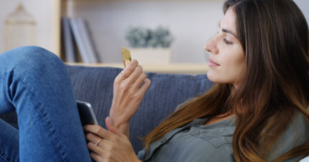 Woman, tablet and checking credit card on sofa for online shopping, security details and internet...