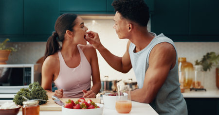 Couple, eating and fruit for fitness at house with healthy meal, nutrition diet and bonding together. People, feeding and strawberry for breakfast snack, morning detox and weight loss with romanceの写真素材