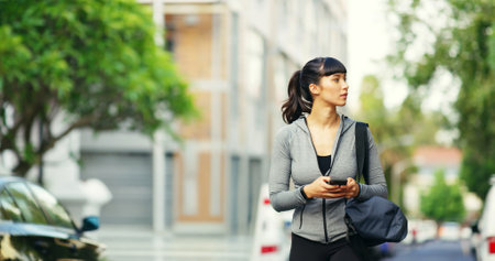 Fitness, woman and walking with phone in city for gym directions, workout location and online map. Athlete, girl or smartphone in nature for communication, text message and destination search in roadの写真素材
