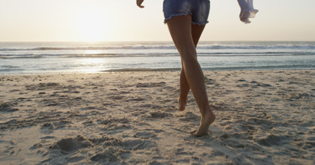 Woman, legs and walking on beach for vacation, explore summer and travel to tropical island. Female person, ocean location and holiday in nature for wanderlust, feet and Bali adventure in sea sandの写真素材