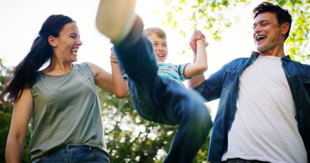 Outdoor, parents and child with swinging for game, playful and relationship with bonding together. Father, mother and boy with flying for childhood fun, coordination and balance with trust in natureの写真素材
