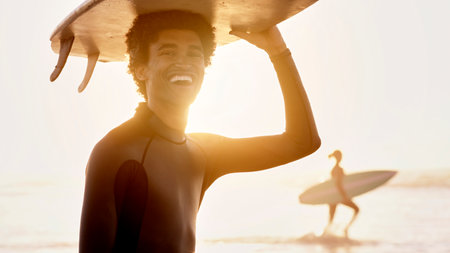 Portrait of happy man, sunset and surfing board on head at beach for summer, freedom and fun. Surfer, guy and laughing at sea, sunshine and adventure for holiday, break or tropical vacation and smileの写真素材