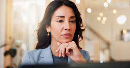 Face, laptop and thinking with business woman at desk in coworking space for online accounting. Computer, problem solving and review with mature accountant in office for administration or planningの写真素材