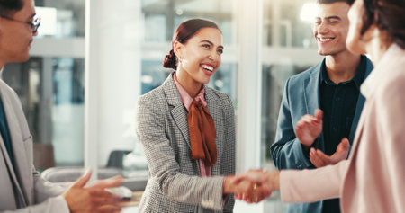 Handshake, applause and happy business people in office for teamwork, collaboration and partnership. Corporate, professional and men and women shaking hands for promotion, agreement and onboardingの写真素材