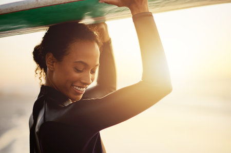 Smile, surfer or happy woman at sea for fitness training, workout or sports exercise at sunset. Surfing surfboard, relax or mixed race athlete smiling on fun summer holiday vacation on Hawaii beachの写真素材