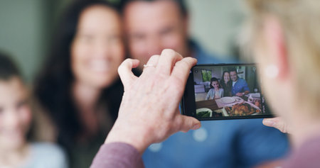 Hand, phone and picture of family in home for bonding, memory or social media post together. Technology, connection and person with cellphone for photography at lunch for profile picture in house.の写真素材
