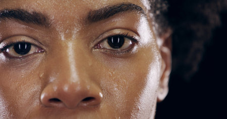 Eyes, fitness and sweat with portrait of woman on black background for intense training or workout. Determination, exercise and health with serious athlete in studio for break, recovery or restの写真素材