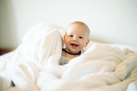 Portrait, kids and blanket with a baby in a bedroom, sitting on a bed in his home for child development. Children, babies and youth with an adorable newborn infant boy in a house for growth or careの写真素材