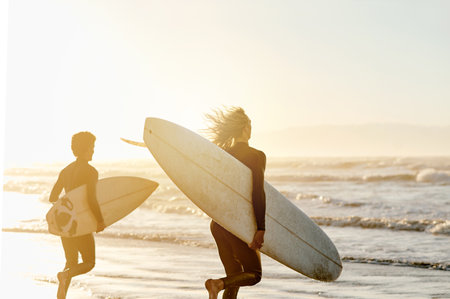 Sunset, enjoying and friends at the beach with surfboards for a hobby, waves and learning an activity. Calm, training and men in the water by the ocean for surfing, competition and sports in the seaの写真素材