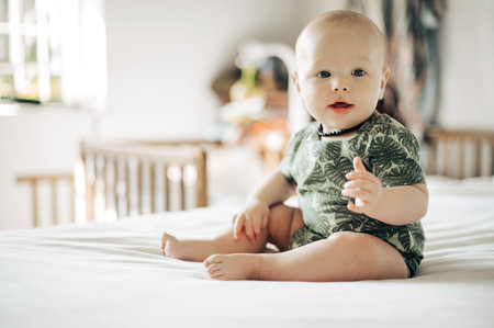 Baby boy, bed and smile in home with excited face, attention and looking with health, youth and...