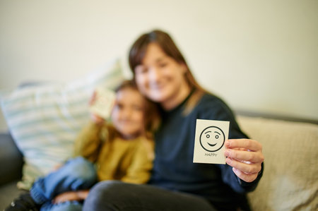 Happy, therapist and a child with an emotion card, showing reaction and feelings in therapy. Together, care and blur of a psychologist with a kid for counseling and working on emotional intelligenceの写真素材