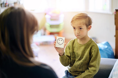 Therapy, emotion and boy talking to a therapist while sitting on a sofa in a psychology clinic. Discussion, flash card and child psychologist helping a kid with his feelings, adhd and mental health.の写真素材