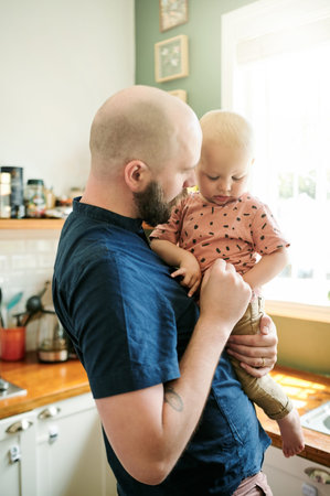 Father, kitchen and dad care for his kid in a home bonding, relax and feeling calm together in a...