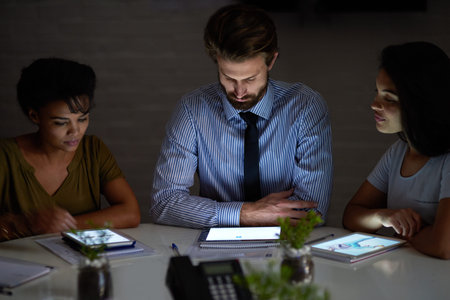 Business people, team and tablet at night in office for reading, meeting and project management....
