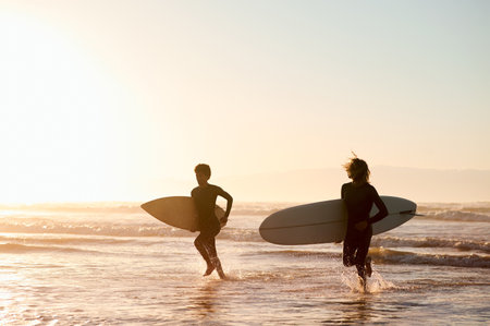 Sunset, beach and friends running with surfboard for ocean fitness while on holiday or vacation mockup. Water sport, travel and men surfers practicing surfing while on tropical weekend trip togetherの写真素材